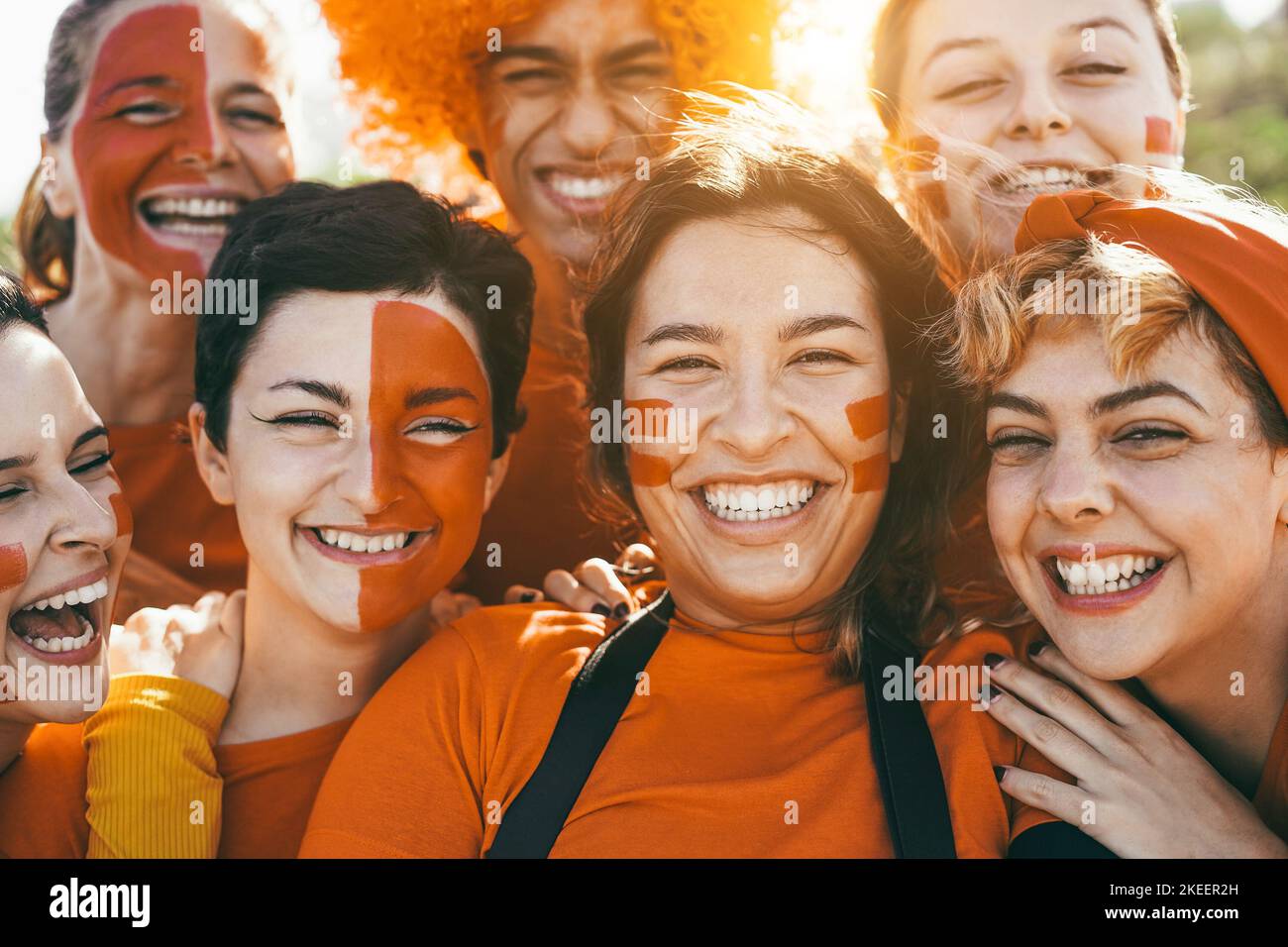 Orange sport fans screaming while supporting their team - Football supporters having fun at competition event - Focus on center girl face Stock Photo