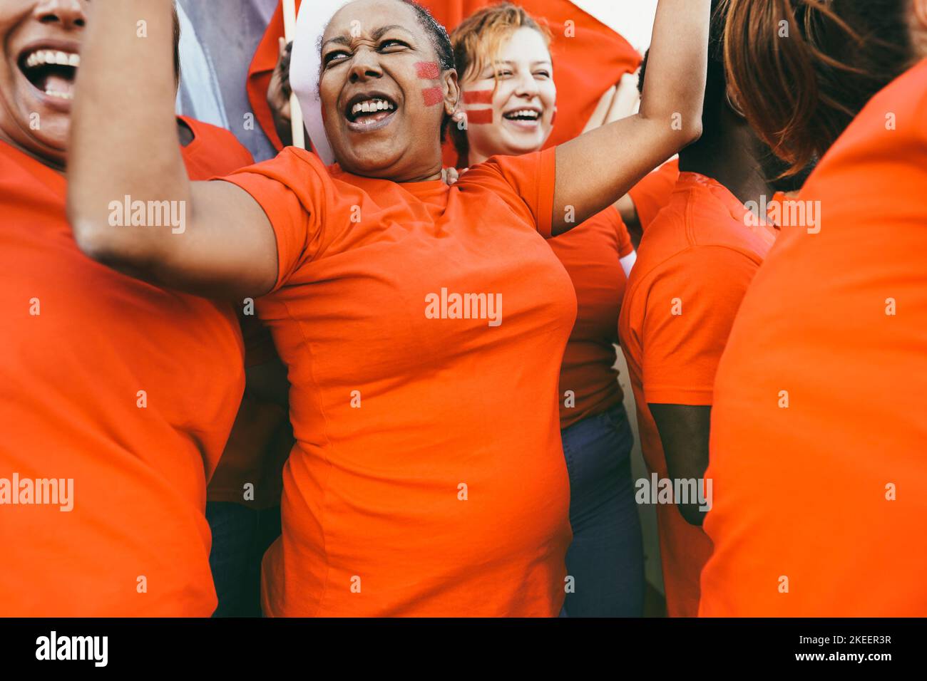 Orange sport fans screaming while supporting their team - Football supporters having fun at competition event - Soft focus on african woman ear Stock Photo