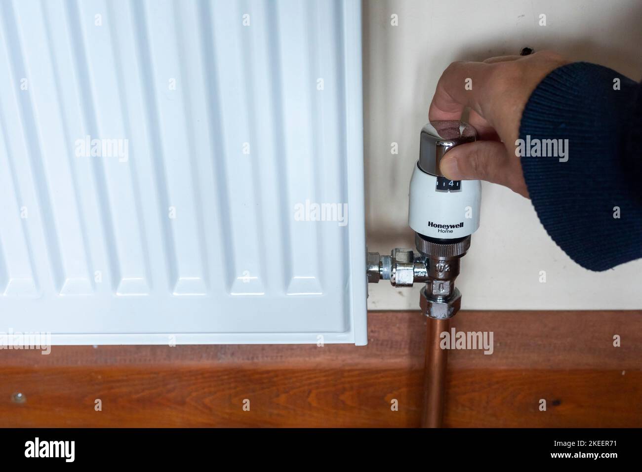 Turning down a thermostatic radiator valve (TRV) on the central heating to reduce the temperature and conserve energy Stock Photo