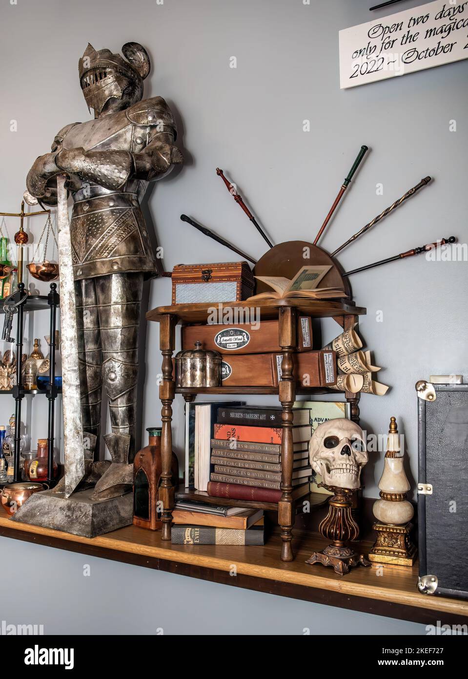 Halloween display with a suit of armor, wizard wands, books and a skull