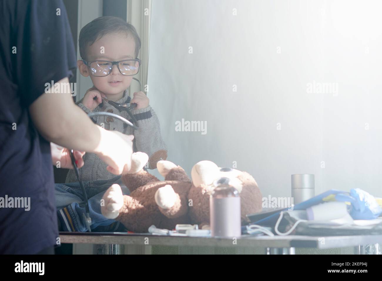 a little boy playing with his teddy bear toy in front of the mirror that he is looking at and holding Stock Photo