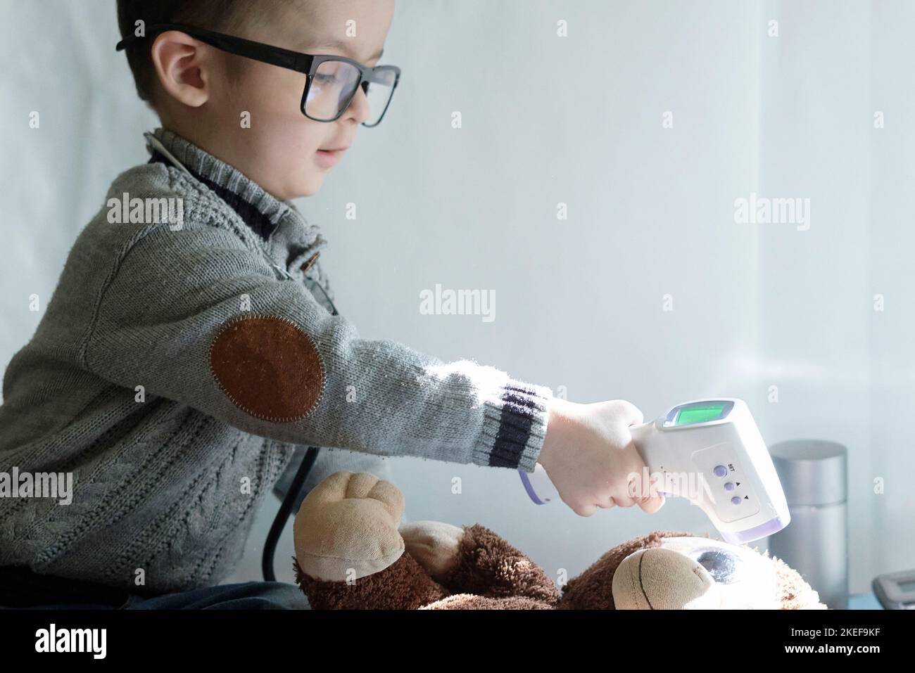 a young boy playing with his teddy bear and the remote control is on