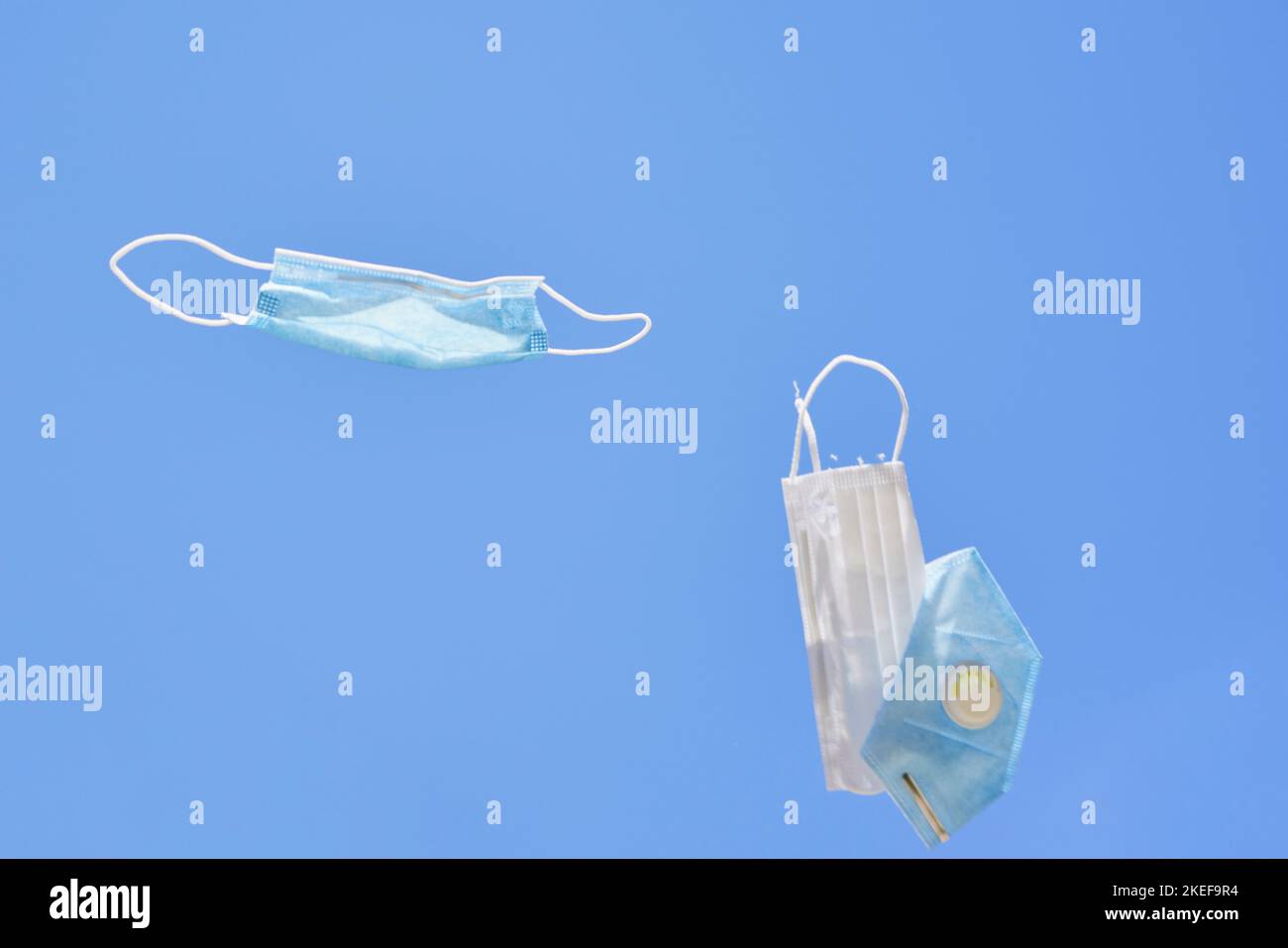 two surgical masks flying in the air with one being attached to it's