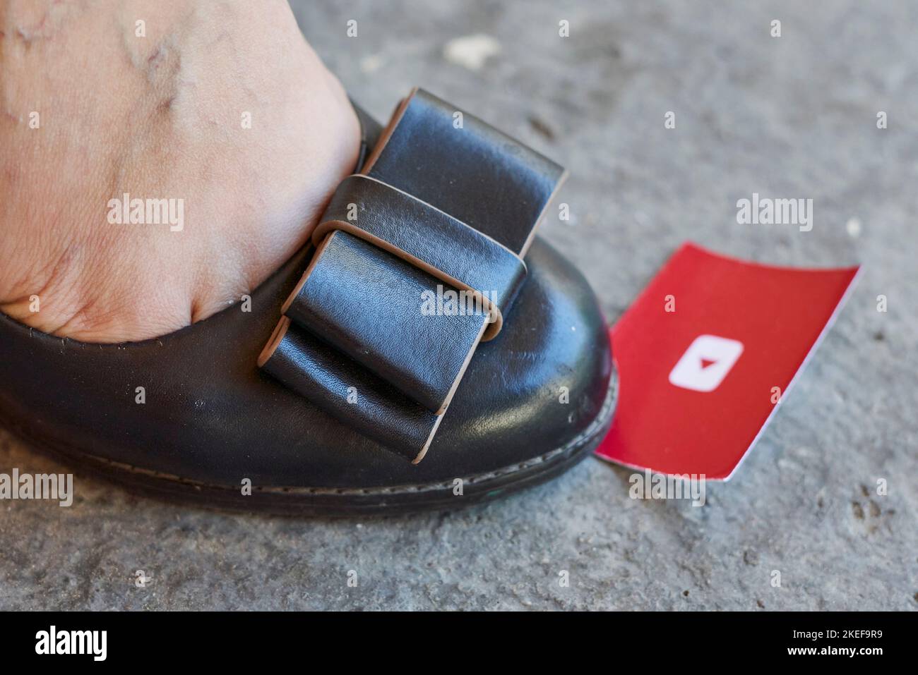 someone's foot with a red card stuck to the bottom of their shoe, which has been worn for several years Stock Photo