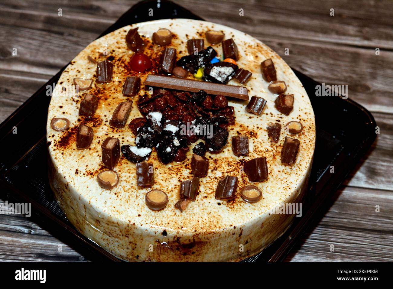 Caramel chocolate festive cake covered with caramel and whipped cream, stuffed with vanilla cream and nuts, and decorated with different types of choc Stock Photo