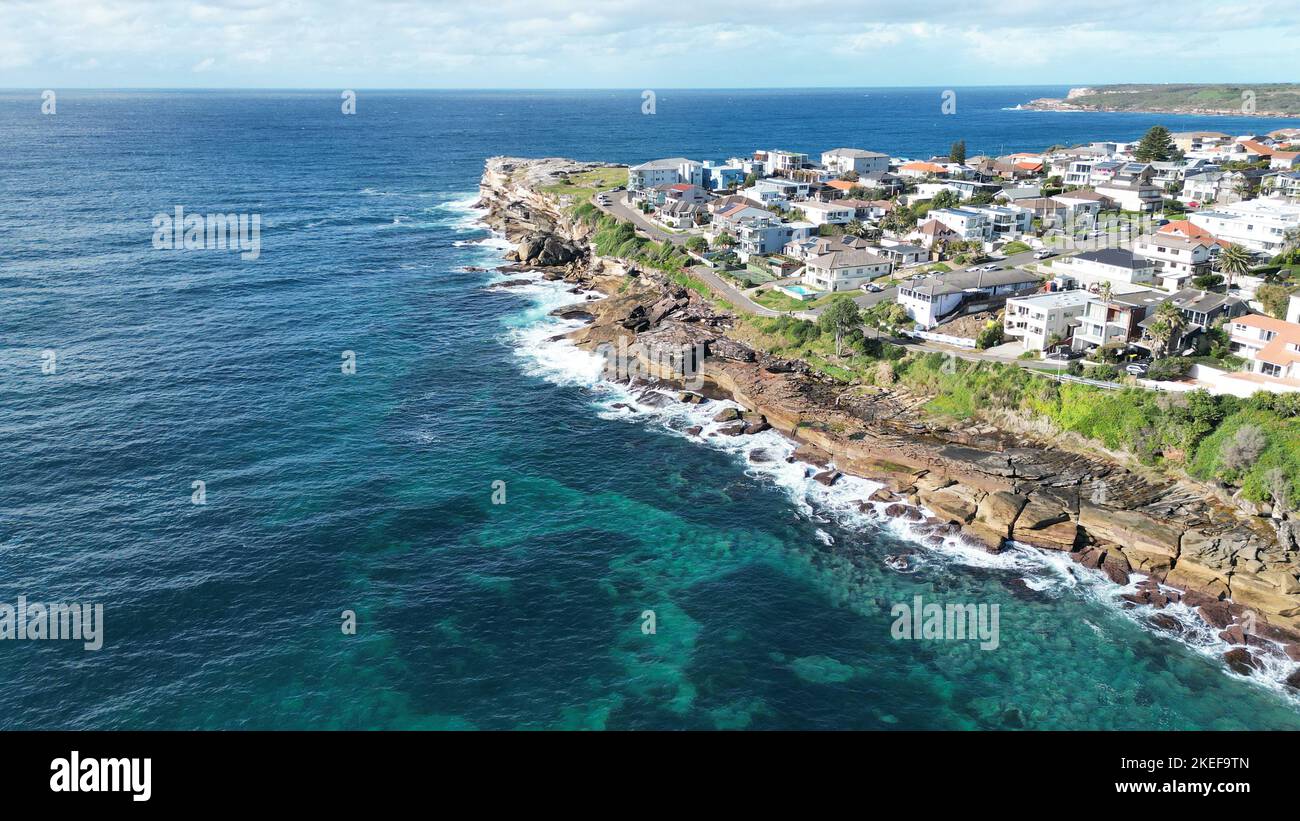 Beautiful aerial view of coastal town with residential buildings and rocky shore surrounded by turquoise ocean in Coogee Australia. Stock Photo