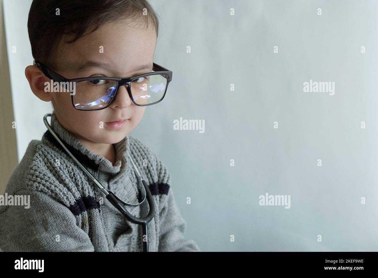 a little boy with glasses and a stel on his head, looking at the camera while he is wearing a stel Stock Photo