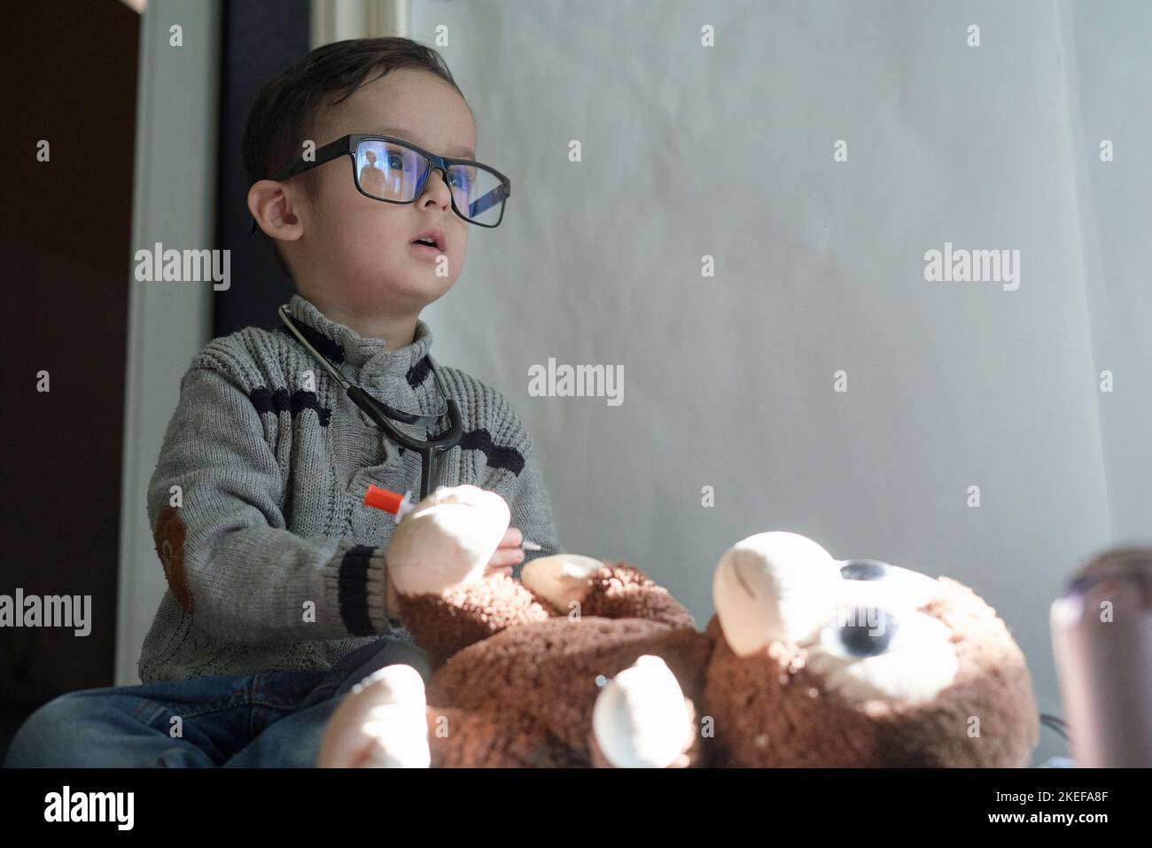 a little boy sitting on the floor with his teddy bear and looking up at ...