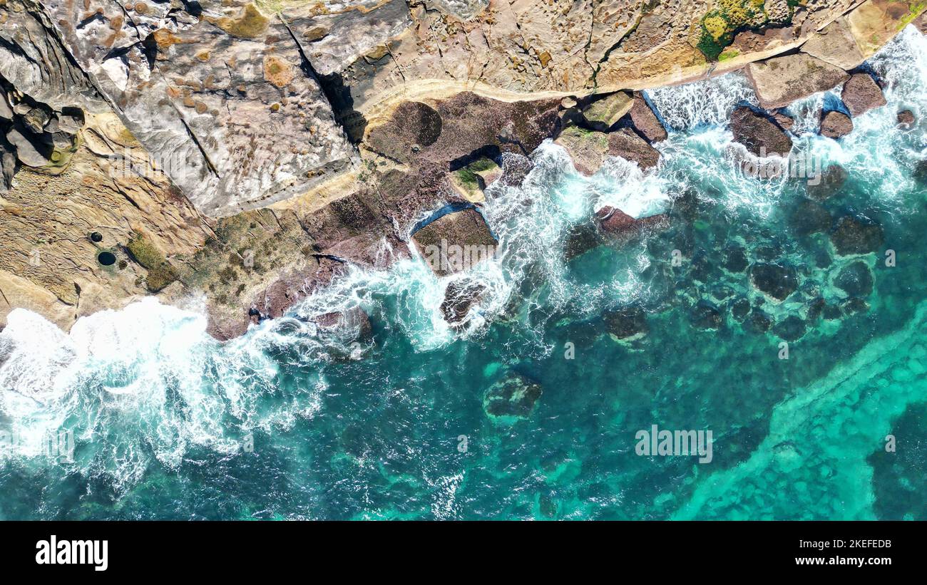An aerial view of aquamarine waves hitting a rocky shore Stock Photo ...
