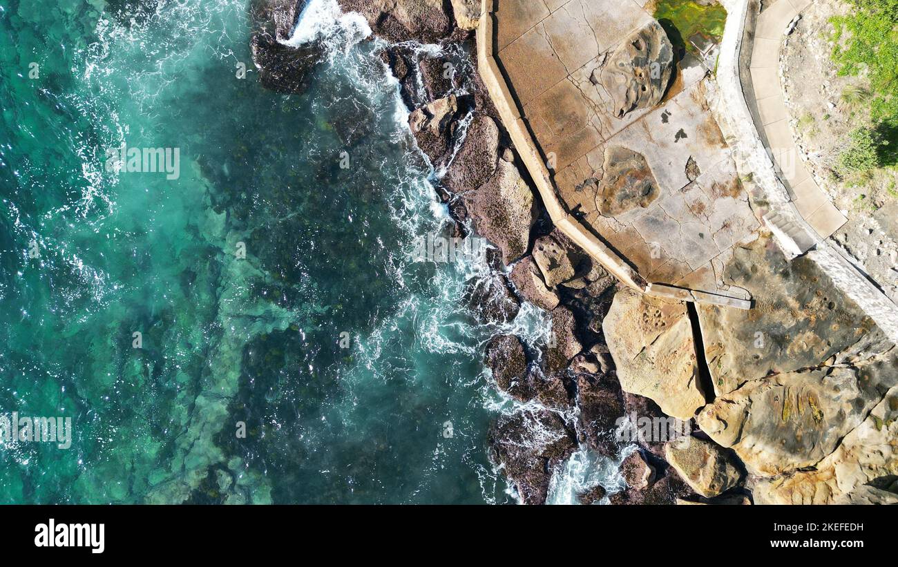 An aerial view of aquamarine waves hitting a rocky shore Stock Photo ...