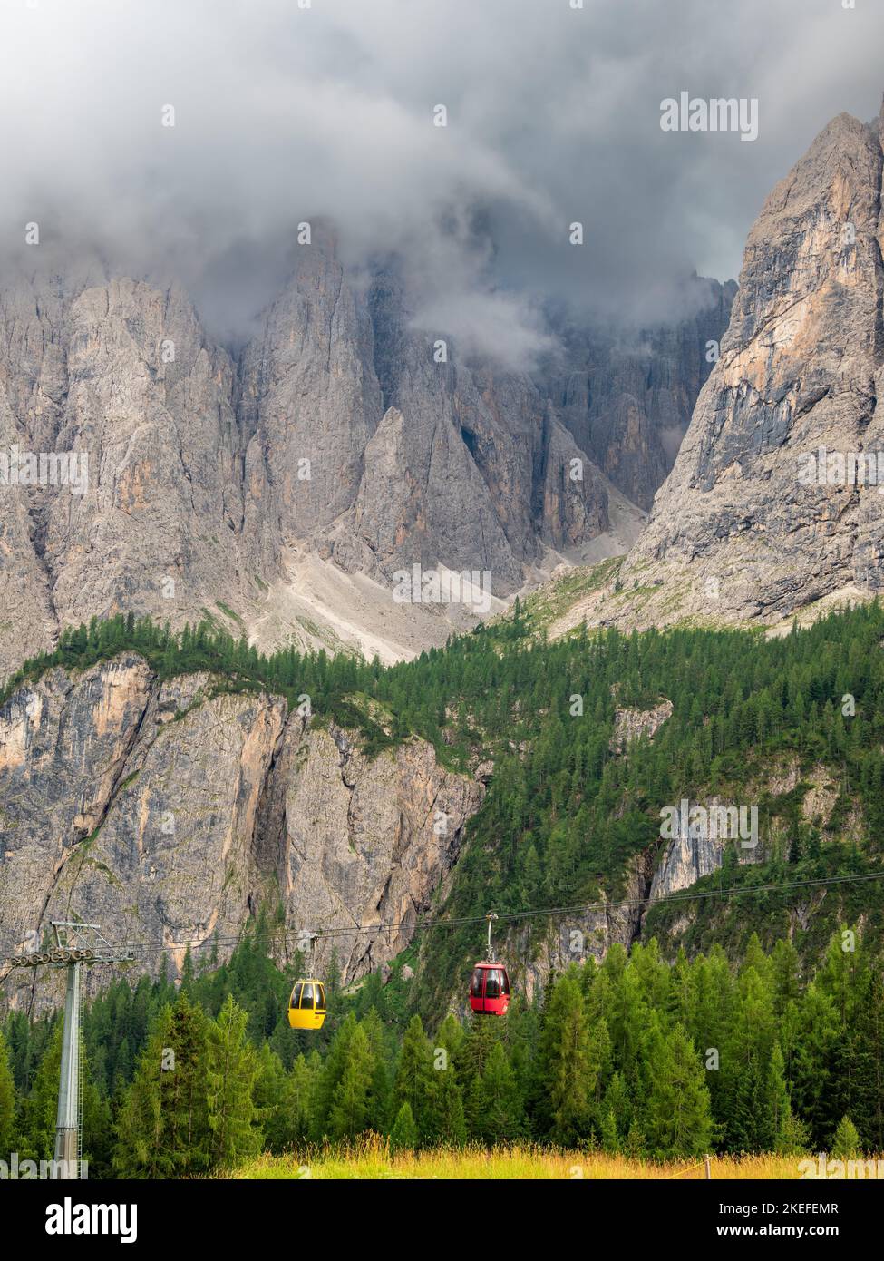 Corvara, Italy - July 22, 2022: Dolomites in the clouds and the red and yellow cable car Stock Photo