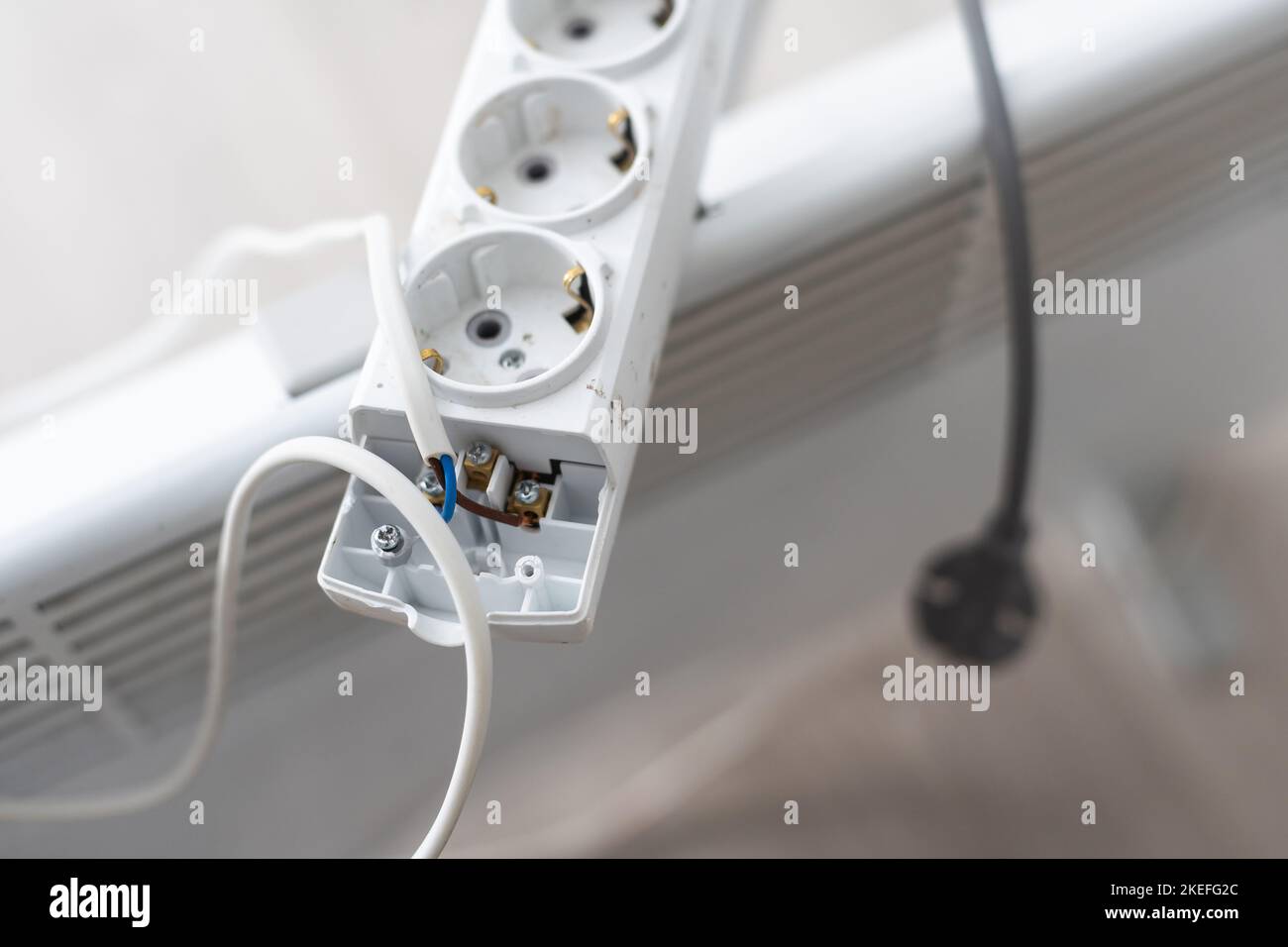 Electric heater plug inserted into extension cord. White radiator for