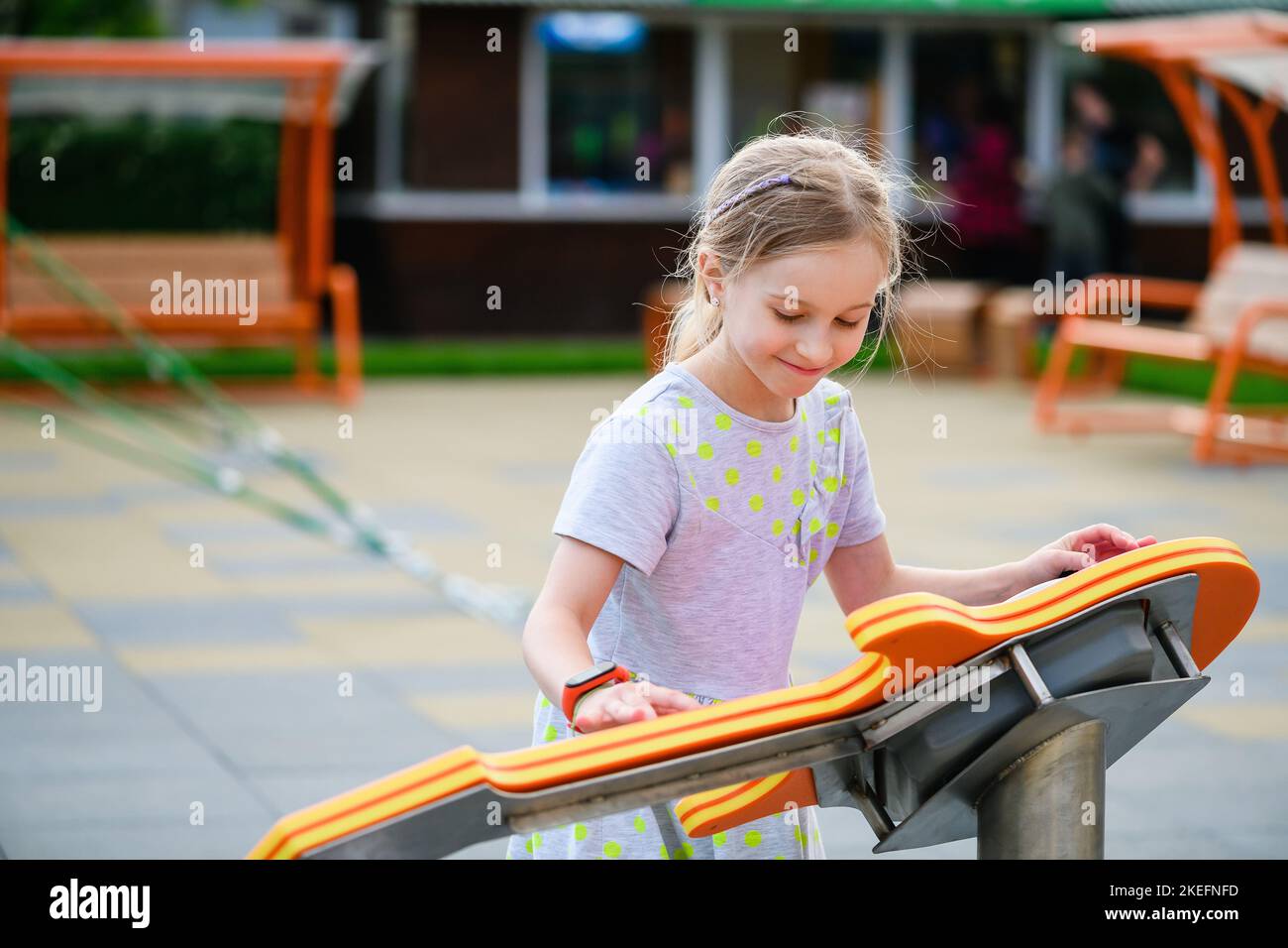 Little child girl elementary school age play interactive game at modern playground outdoors, learning with fun Stock Photo
