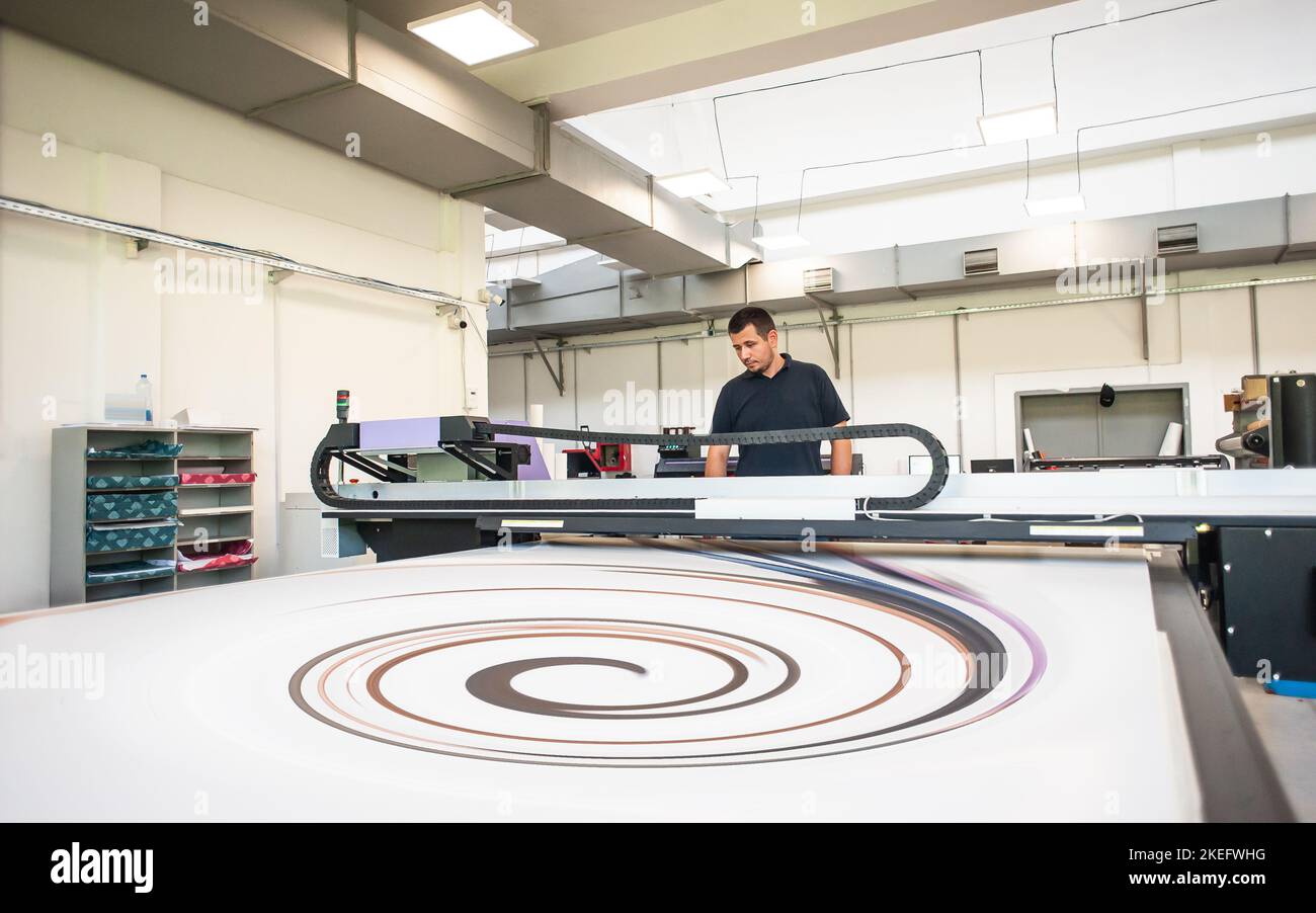 In the printing house, an experienced technician works on a UV printer. Production work. Check