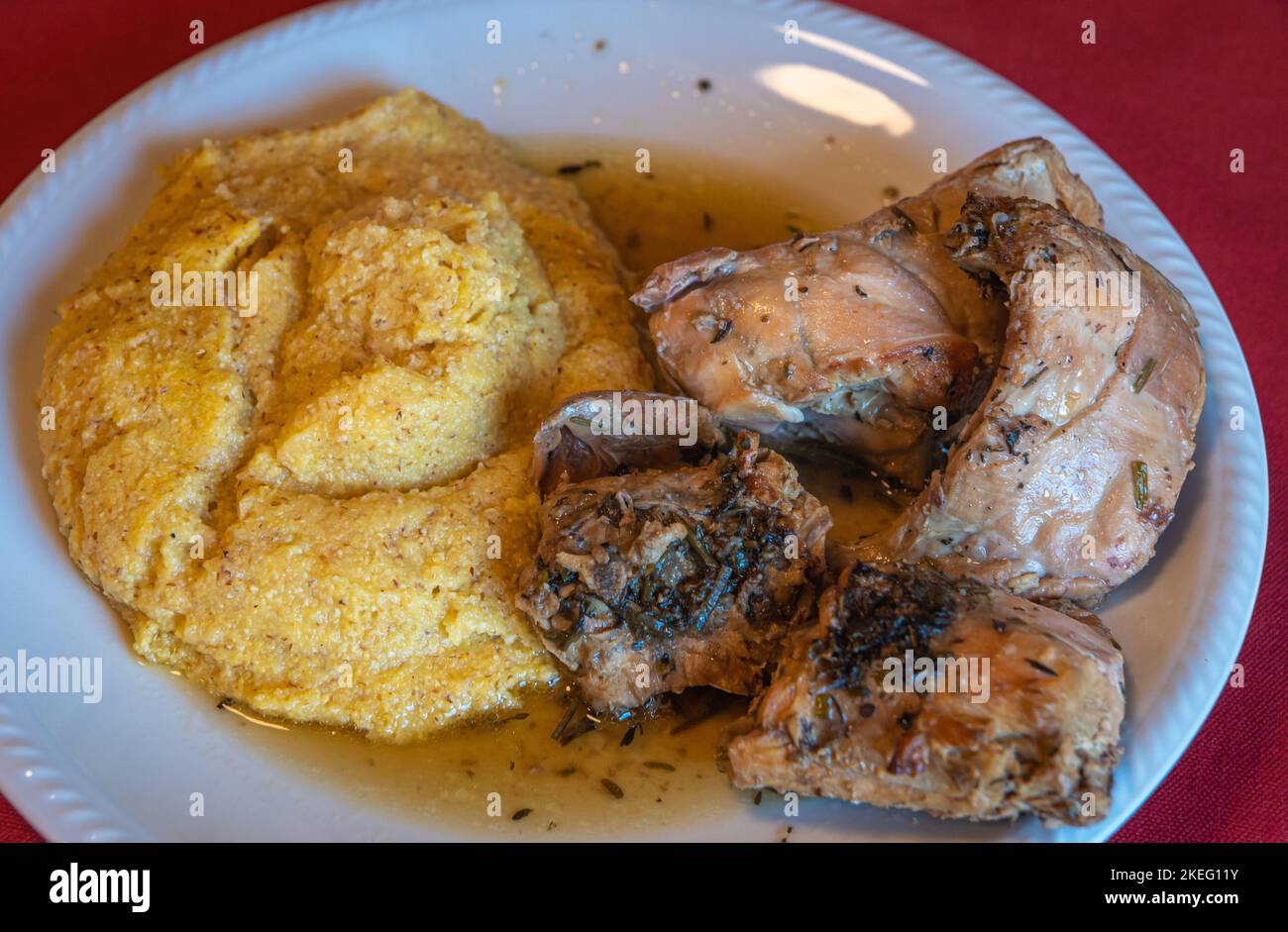 rabbit meat with polenta. local corn porridge with stew pieces of rabbit. Selective focus with shallow depth of field. Traditional italian cuisine. Stock Photo