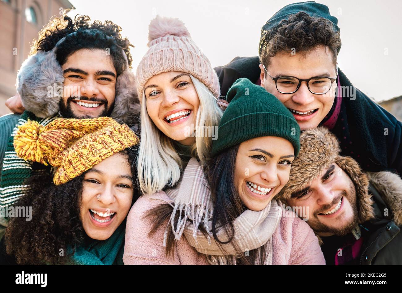International guys and girls taking funny selfie on warm fashion clothes - Happy life style concept with millenial people having fun together out side Stock Photo