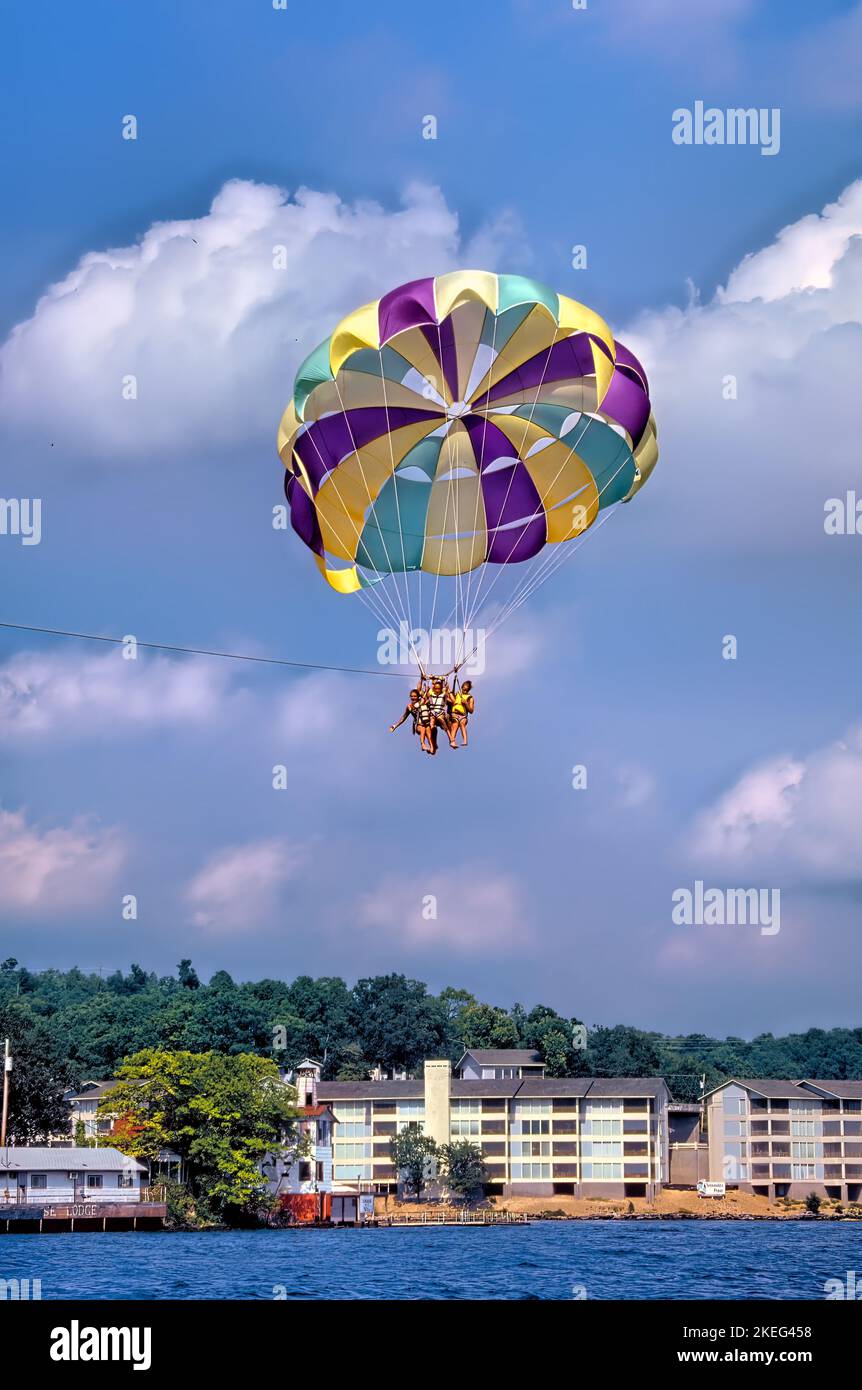 Three people using one chute are seen parasailing on Lake of the Ozarks in Missouri Stock Photo