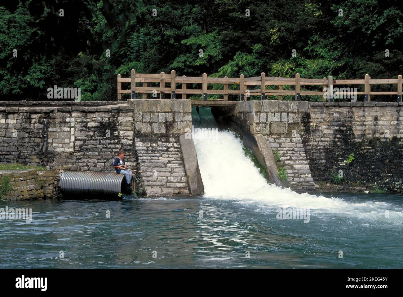 A lone boy fishes by the spillway at Roaring River State Park near Cassville, Missouri on July 2, 2005. Roaring River is one of Missouri's cold water Stock Photo