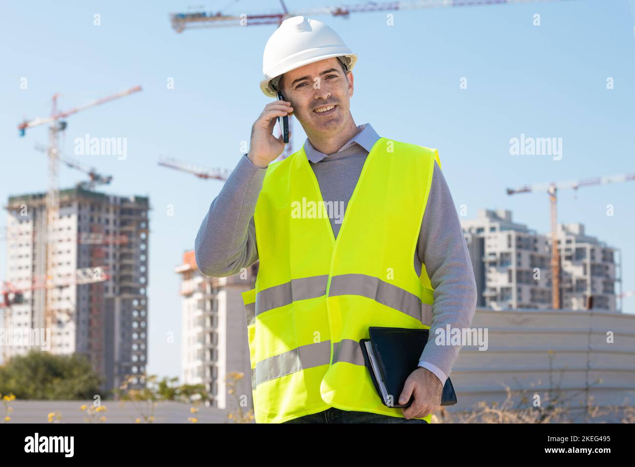 Professional builder standing with a notebook in front of the construction site Stock Photo