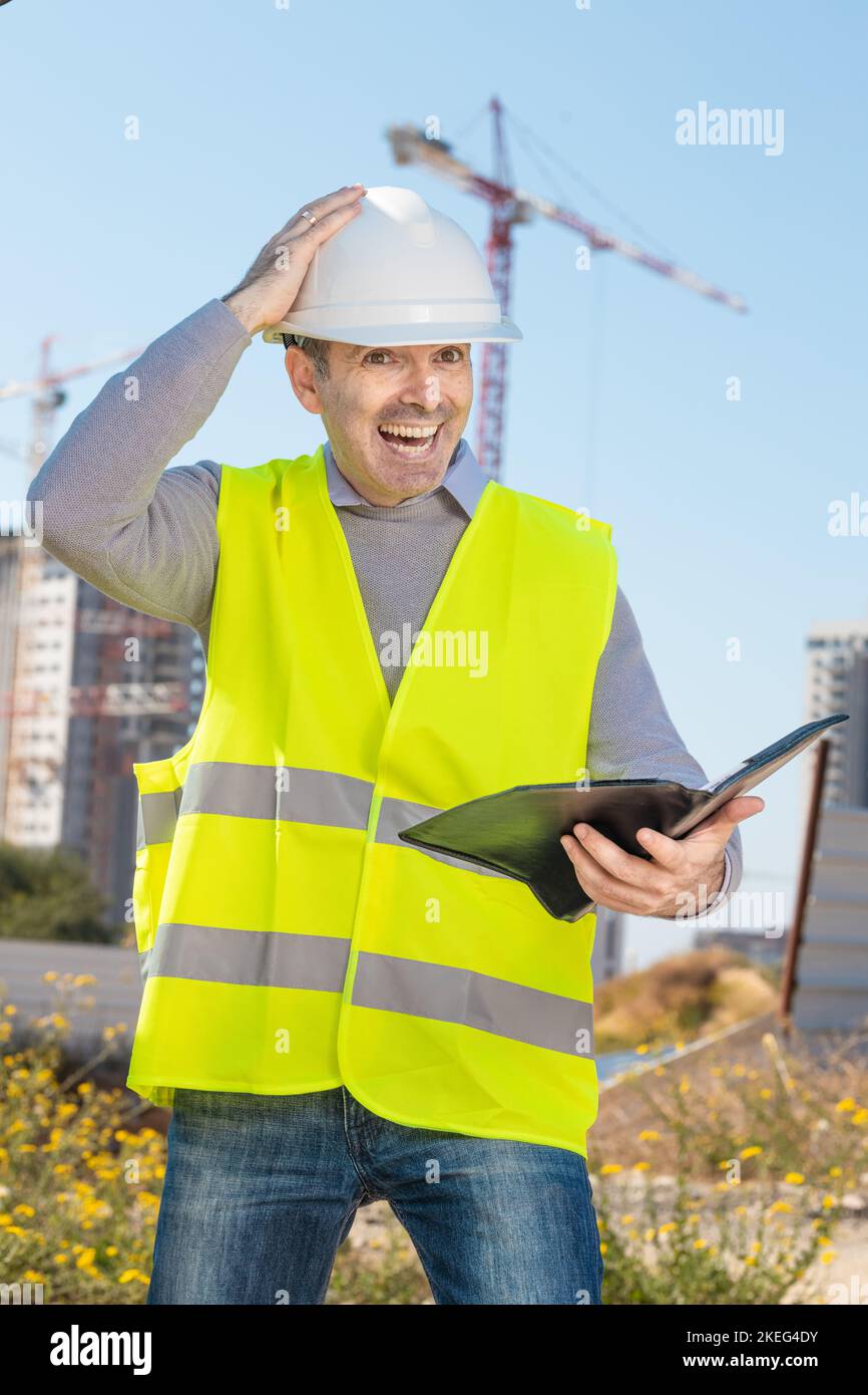 Professional builder standing with a notebook in front of the construction site Stock Photo