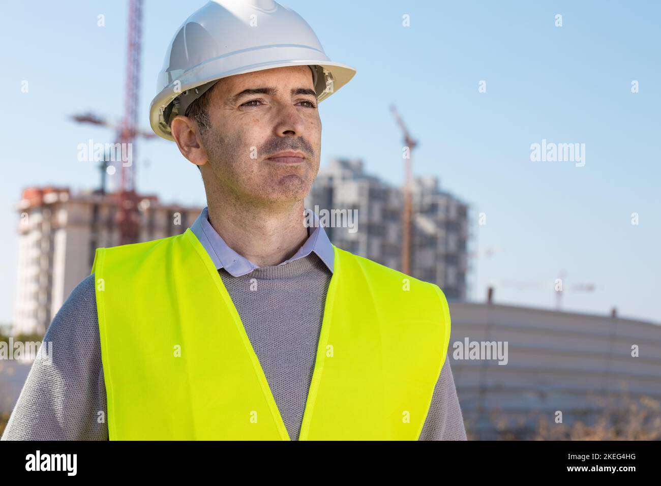Professional builder standing with notebook in front of the construction site Stock Photo