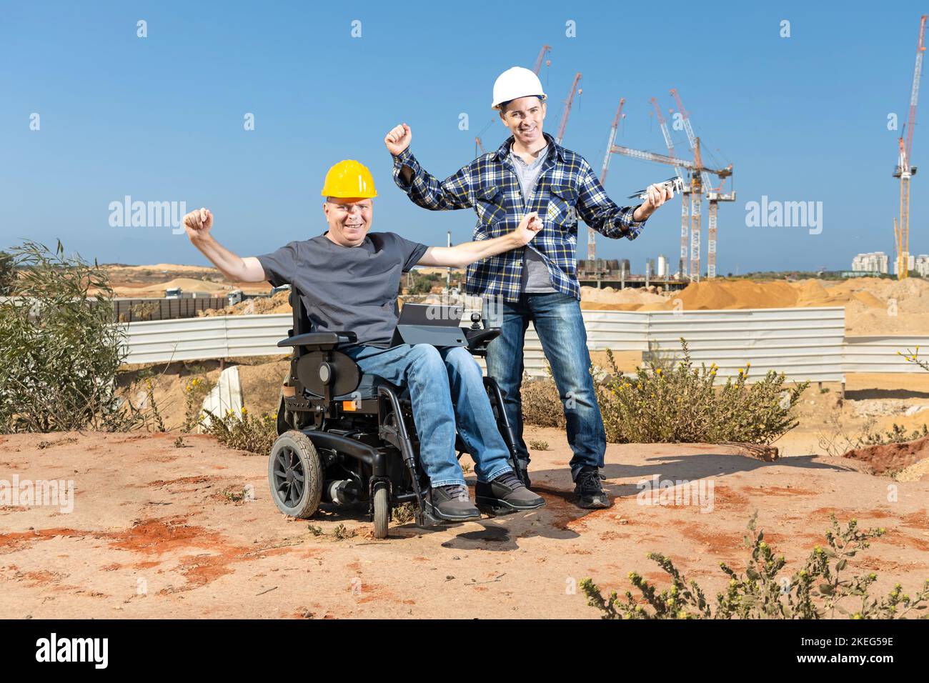 Two professional builders standing with a computer in front of the construction site Stock Photo