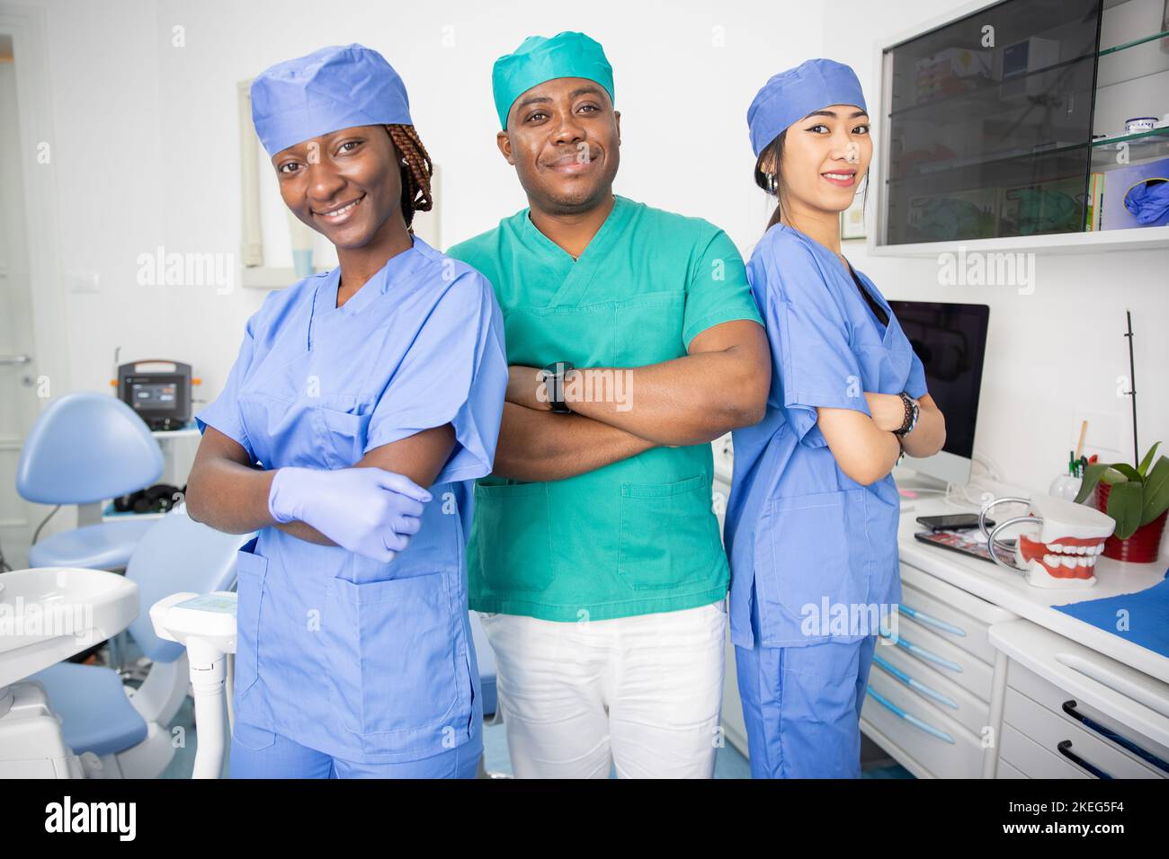 Three dentists pose smiling in a dental office, work in the health