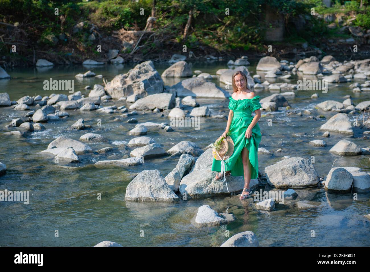 a girl in a green dress is standing by the river Stock Photo - Alamy