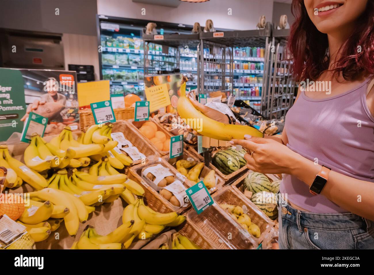 25 July 2022, Munster, Germany: Client woman choosing and buying bananas at grocery store or supermarket Stock Photo