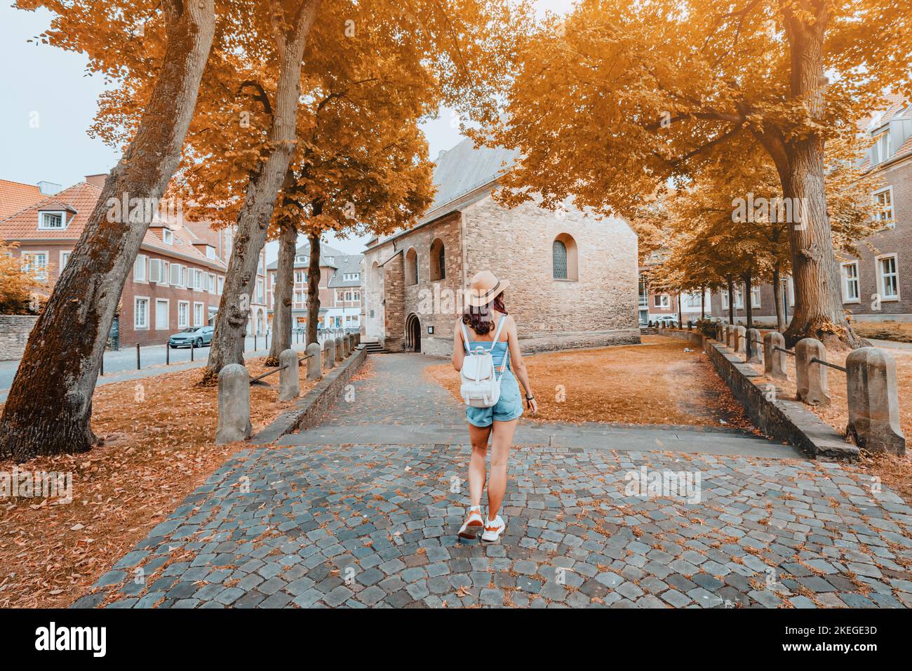 Woman tourist with backpack walking by old european city street at colorful autumn or fall time Stock Photo