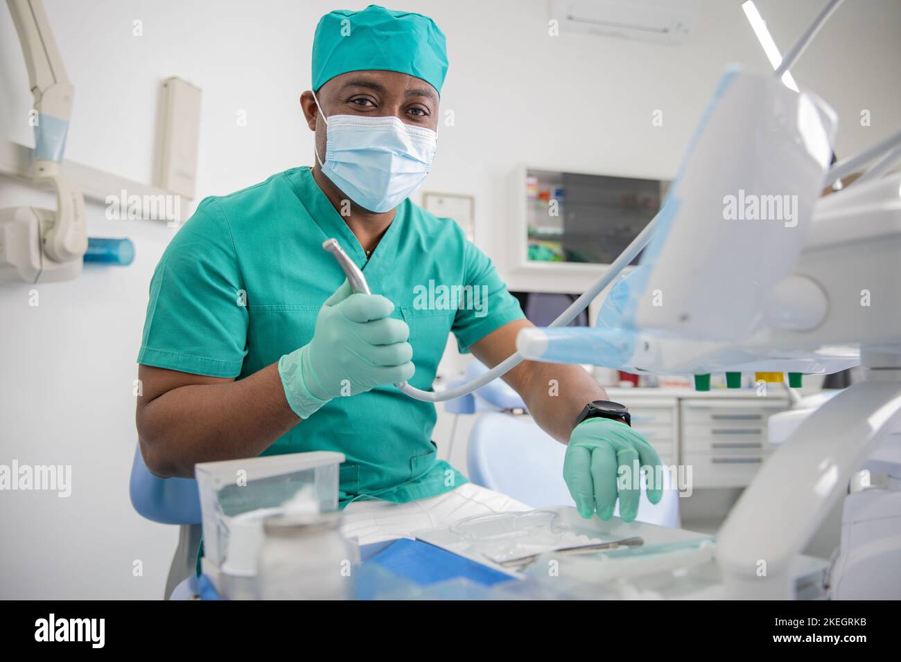 African dentist holds a dental drill in his clinic, health care worker