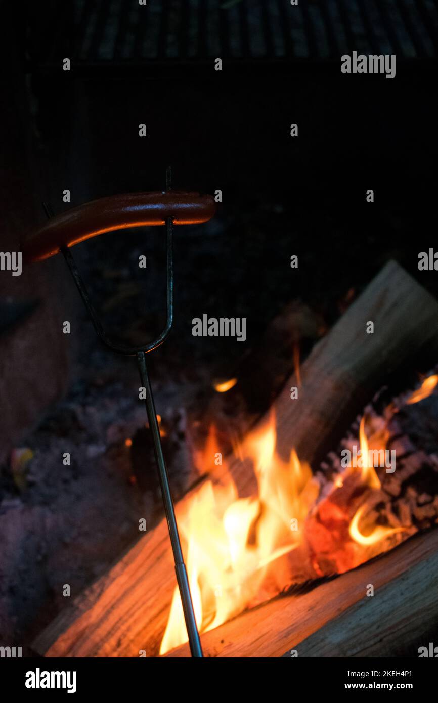 Roasting a hotdog over a campfire Stock Photo
