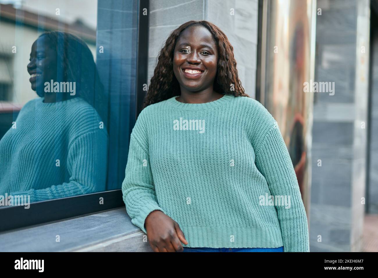 Young african woman smiling happy leaning on the wall Stock Photo - Alamy