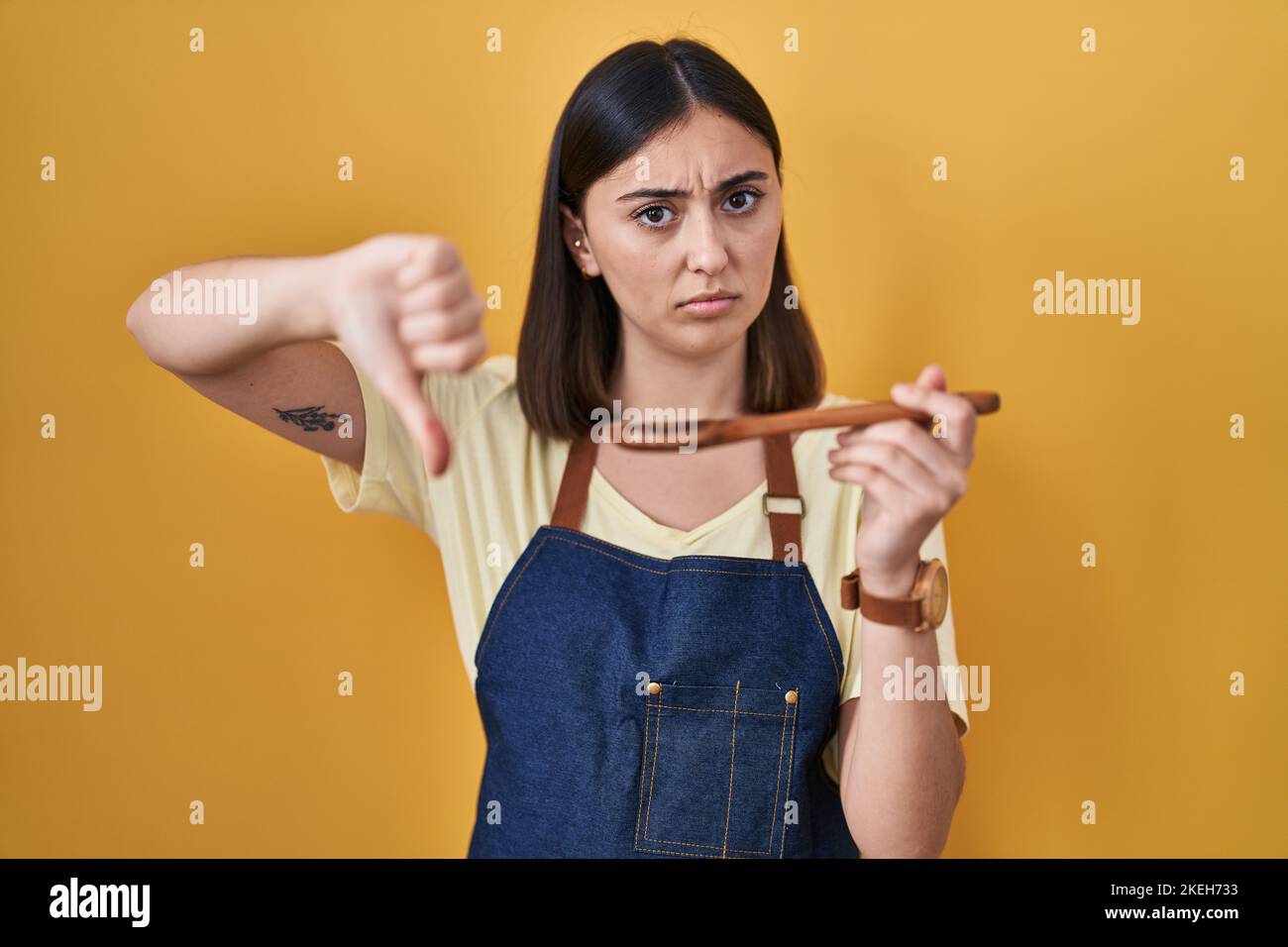 Hispanic girl eating healthy wooden spoon looking unhappy and angry ...