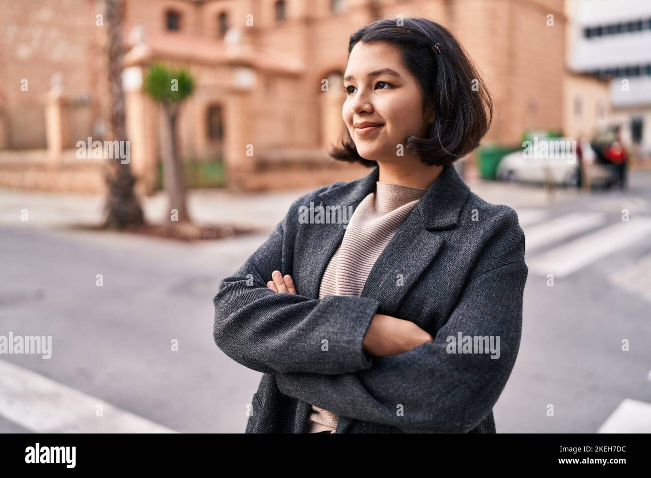 Young woman standing with arms crossed gesture looking to the side at ...