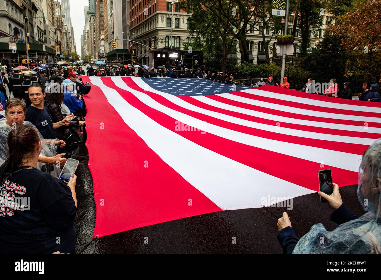 New York, United States of America. 11 November, 2022. U.S. sailors assigned to the San Antonio-class amphibious transport dock ship USS Arlington and II Marine Expeditionary Force members join civilians in unfurling a giant American flag during the New York City Veterans Day Parade, November 11, 2022 in New York City, NY. Credit: MCS John Bellino/US Navy/Alamy Live News Stock Photo
