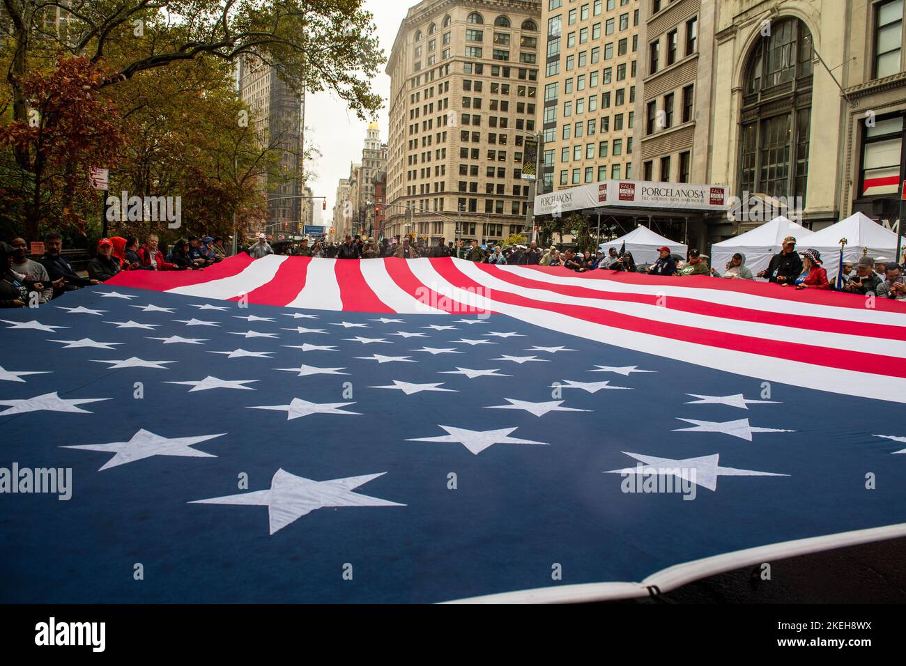 New York, United States of America. 12 November, 2022. U.S. sailors assigned to the San Antonio-class amphibious transport dock ship USS Arlington and II Marine Expeditionary Force members join civilians in carrying a giant American flag during the New York City Veterans Day Parade, November 11, 2022 in New York City, NY. Credit: MC3 Roan Smith/US Navy/Alamy Live News Stock Photo