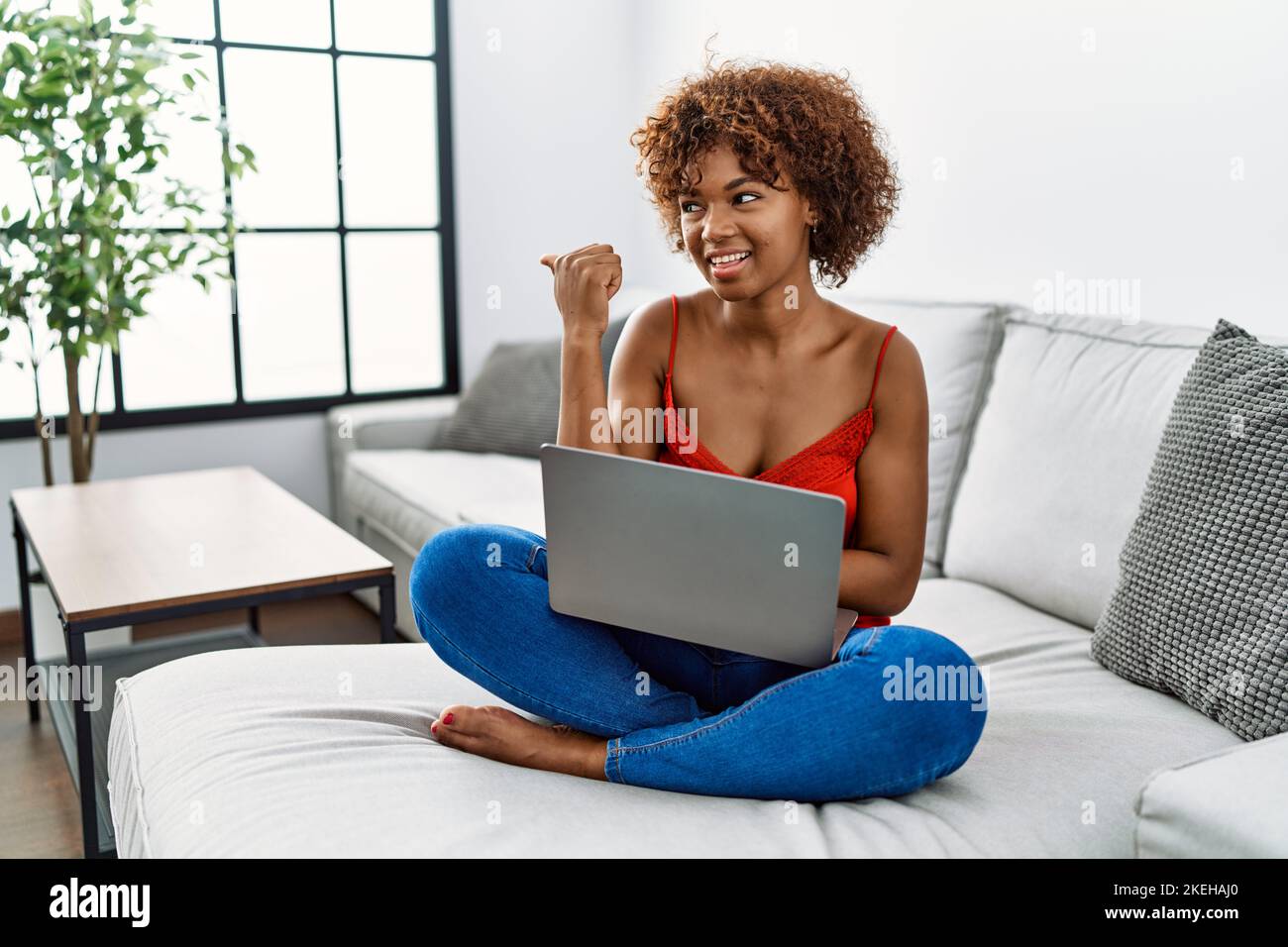 Young african american woman sitting on the sofa at home using laptop ...