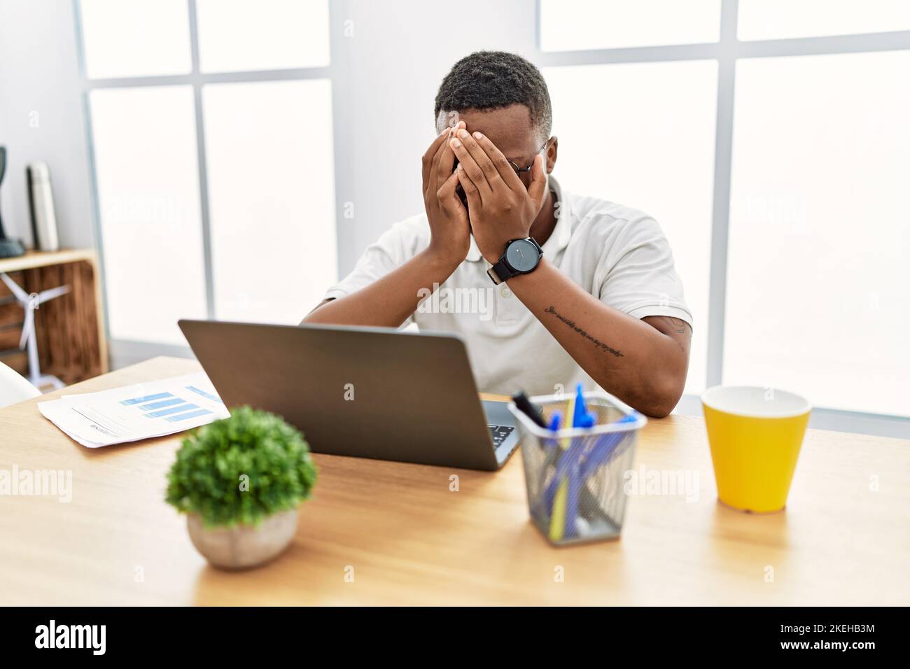 Young african man working at the office using computer laptop with sad ...