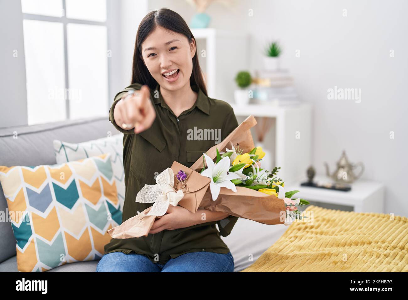 Chinese young woman holding bouquet of white flowers pointing to you ...