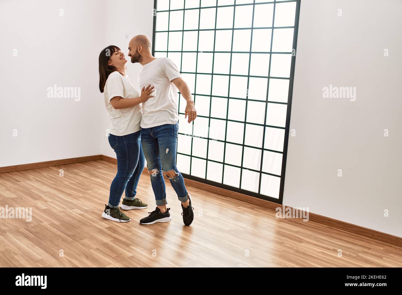 Young hispanic couple smiling happy dancing at empty new home Stock ...