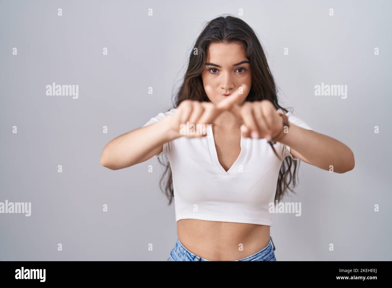 Young teenager girl standing over white background rejection expression ...