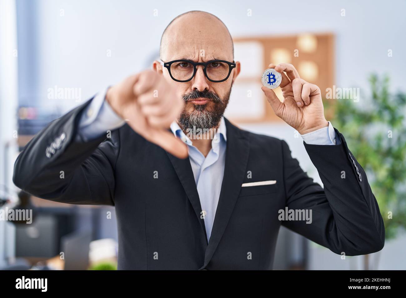Young hispanic business man holding virtual currency bitcoin with angry ...