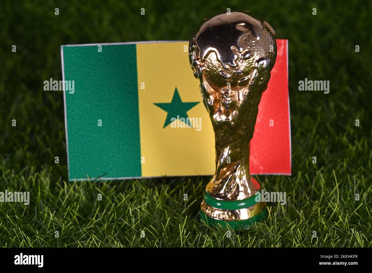 November 13, 2022, Doha, Qatar. FIFA World Cup trophy on the background of the flag of Senegal on the green lawn of the stadium. Stock Photo