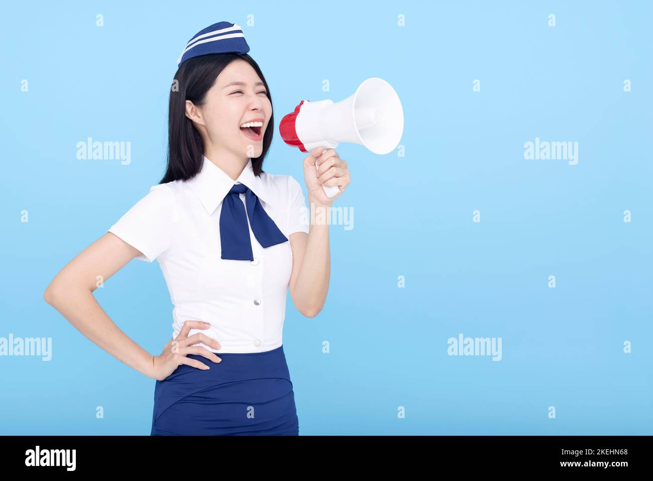 Airplane stewardess  woman isolated on blue background shouting through the megaphone Stock Photo
