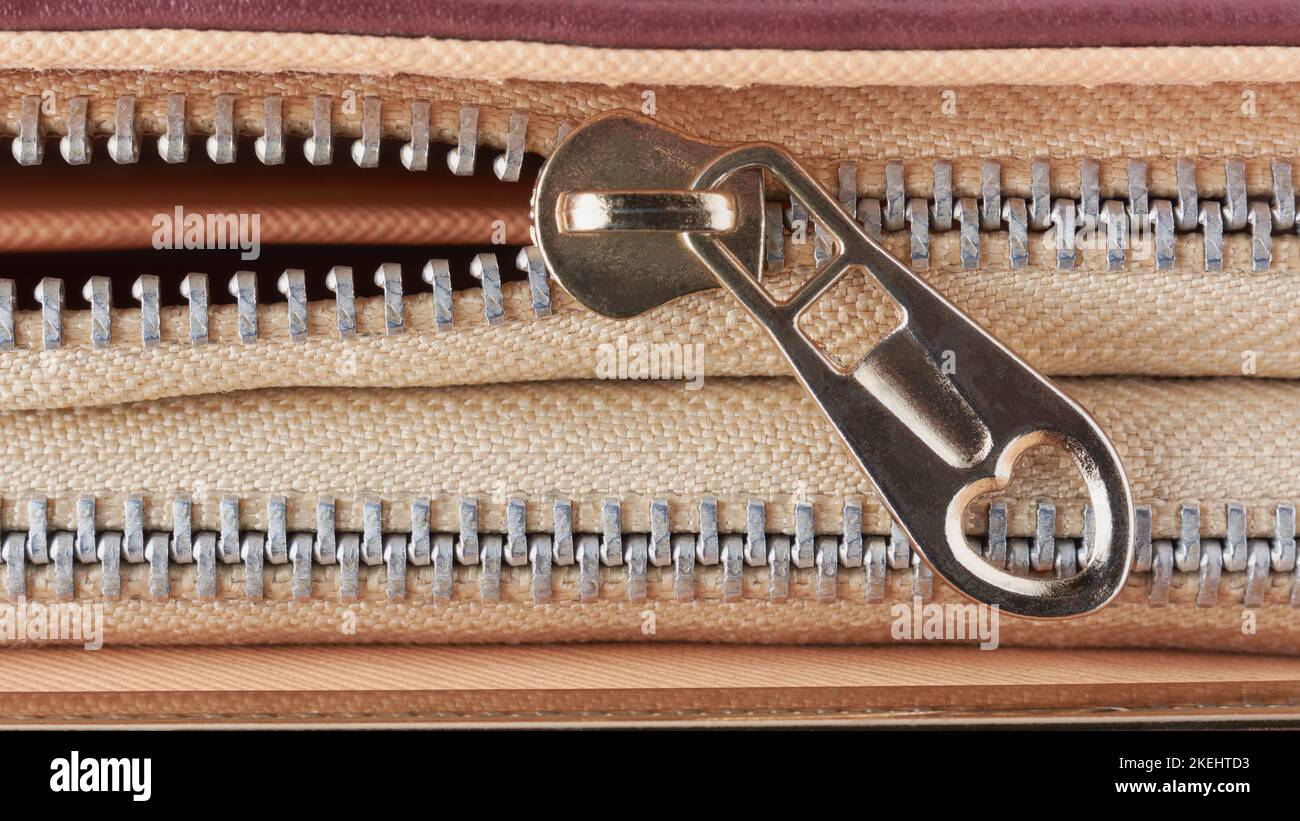 close-up of gold color metal zipper with heart shape hole in the pull tab, taken from above with copy space Stock Photo