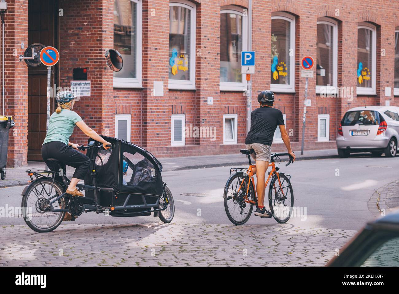 25 July 2022, Munster, Germany: A sports family - a father and mother with a child ride bicycles through the streets of an old European city Stock Photo