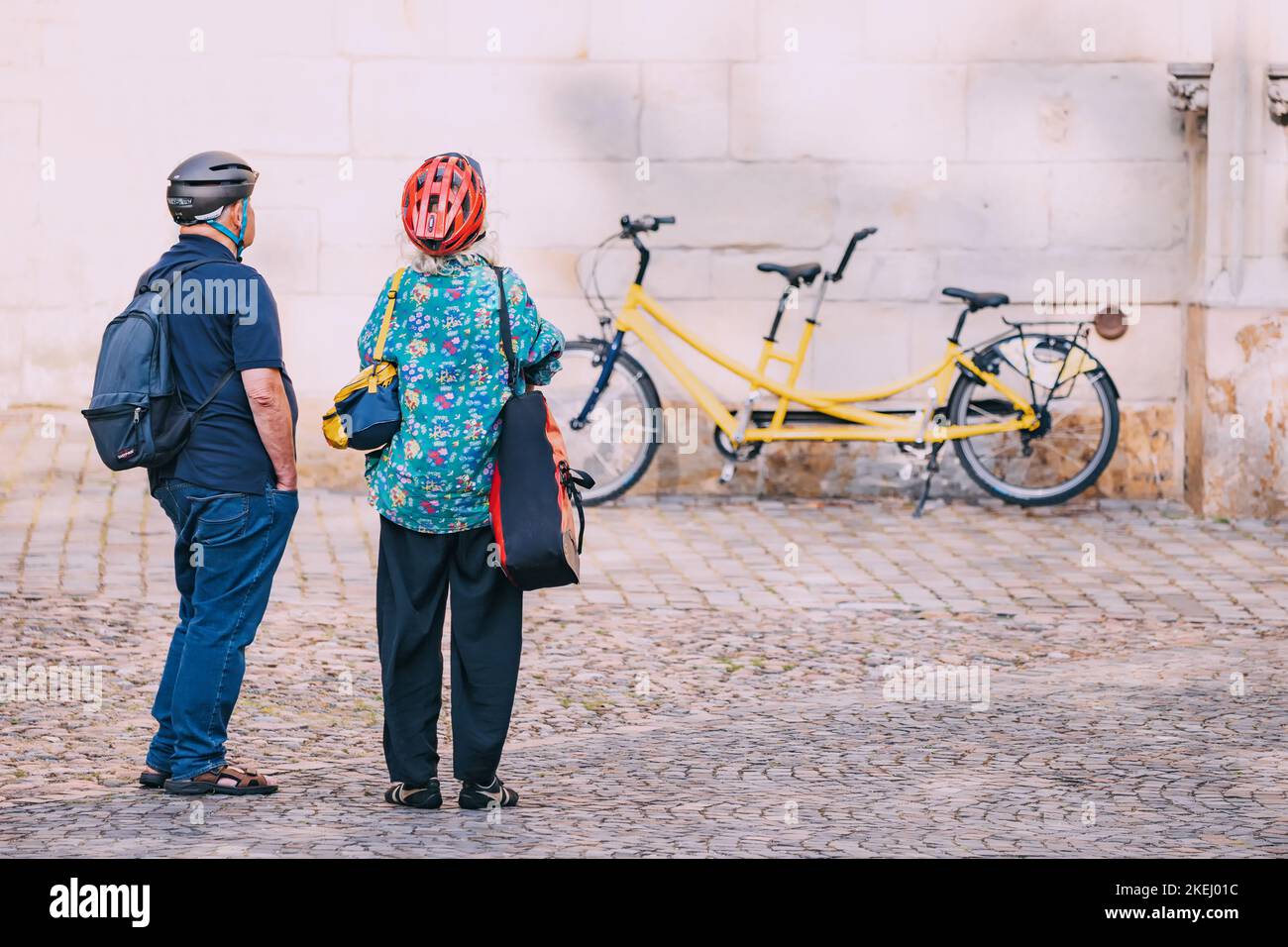 25 July 2022, Munster, Germany: An elderly senior couple arrived on a tandem bicycle and explore the sights of the old town Stock Photo