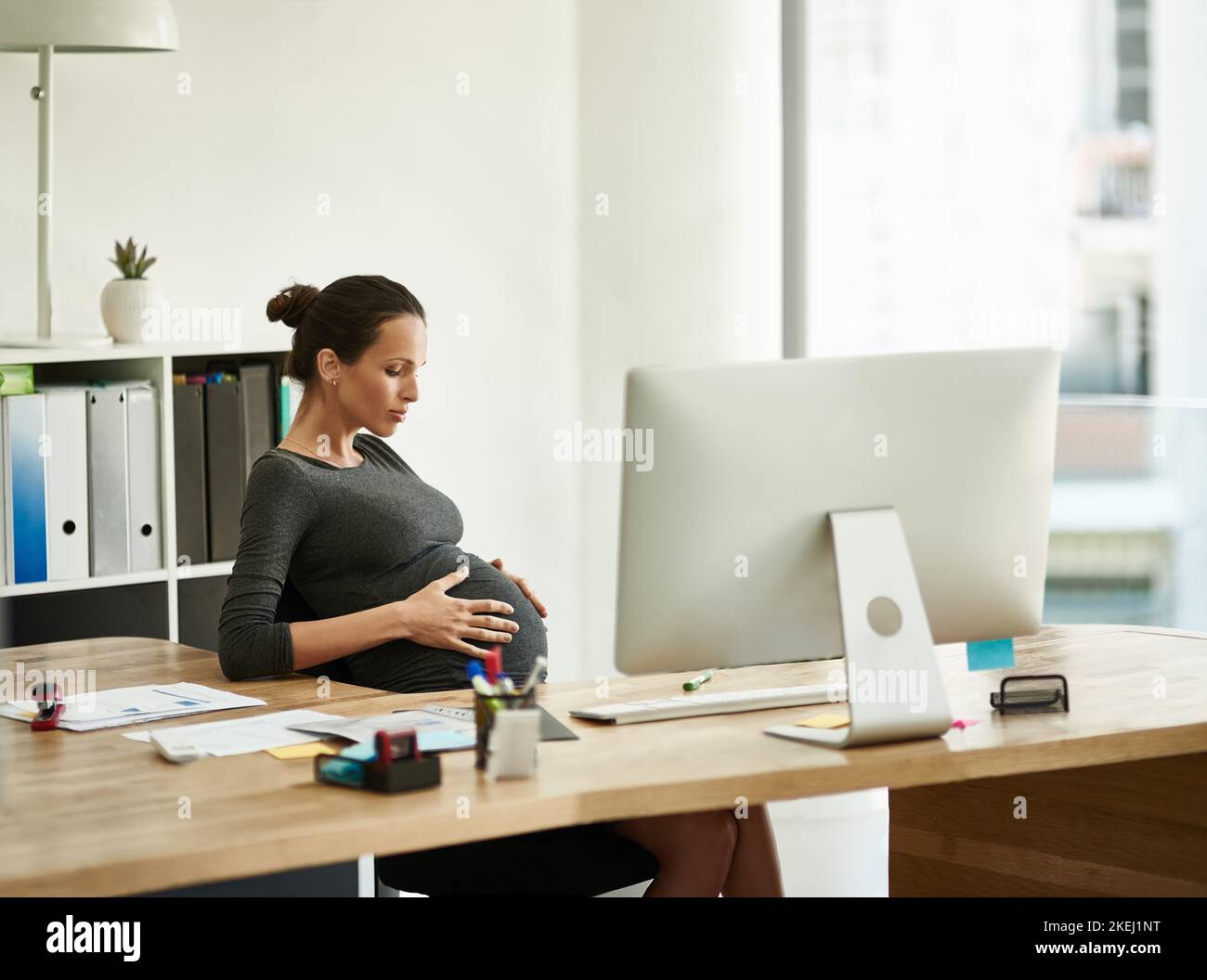 Shes getting bigger by the workday. a pregnant businesswoman sitting at