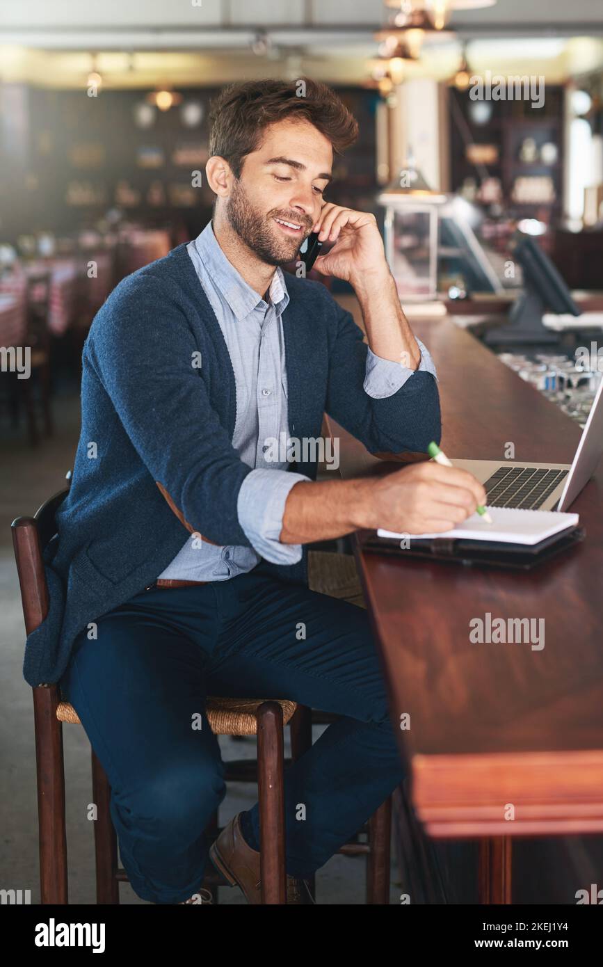 Sure...whats the number. a handsome young man using his laptop and cellphone in a bar. Stock Photo